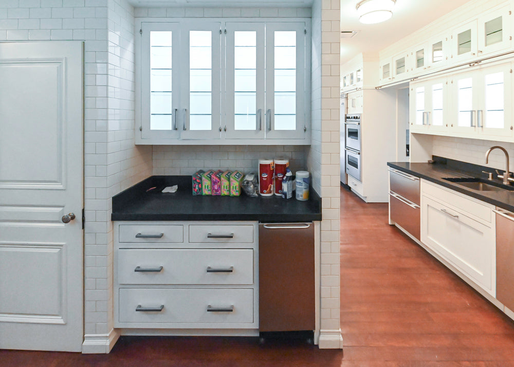 Modern kitchen with white cabinets, black countertops, and stainless steel appliances.