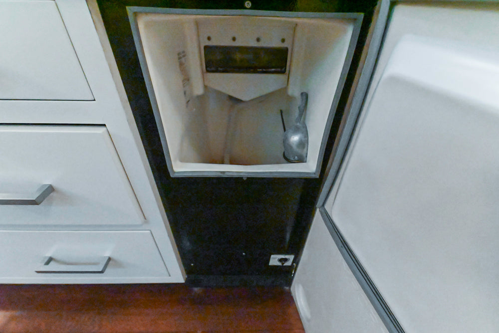 Small kitchen appliance embedded in a white cabinet with a metallic handle.