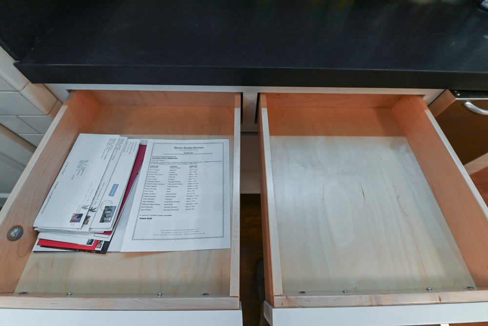 Open wooden drawer with printed documents and an empty one below.