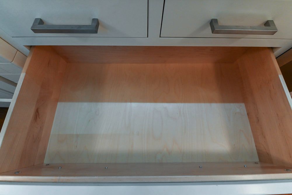 Open wooden drawer with metal tray inside, likely in a kitchen setting.