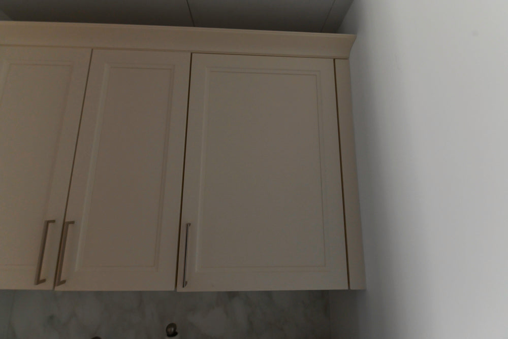 White kitchen cabinets with silver handles on a white wall.