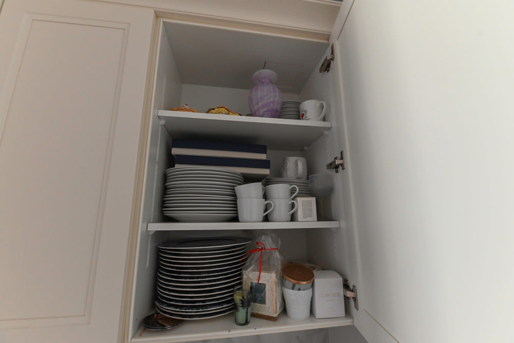 Open kitchen cabinet with dishes and kitchenware inside