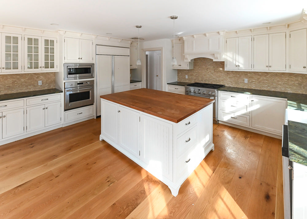 Modern kitchen with white cabinets, wooden island, and stainless steel appliances.