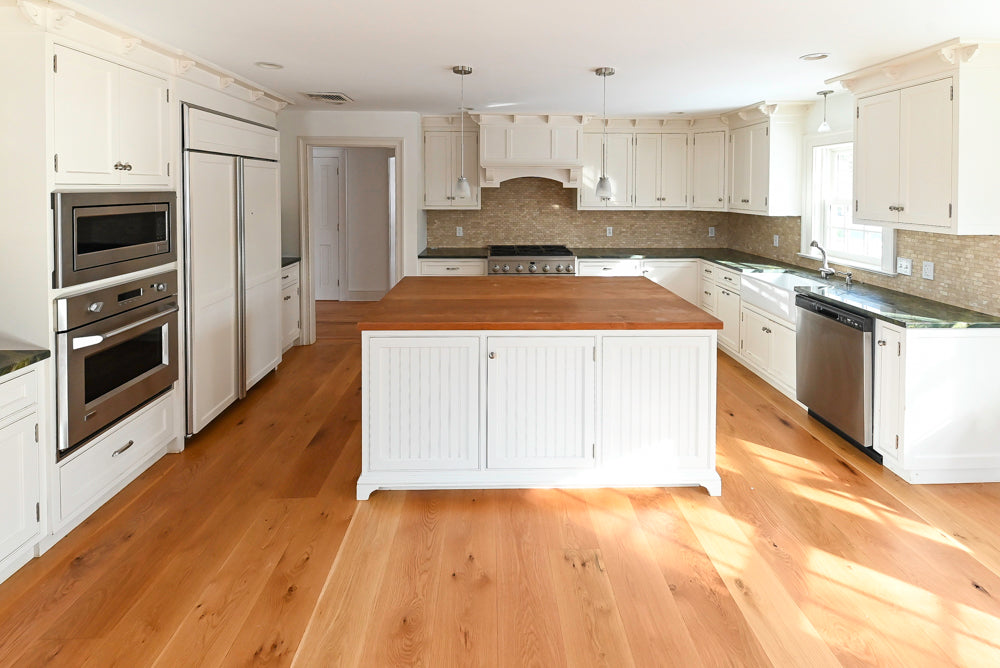 Modern kitchen with white cabinets, wooden floor, and island.