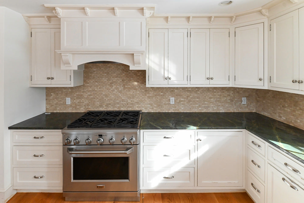 Modern kitchen with white cabinets, black countertops, and stainless steel oven.