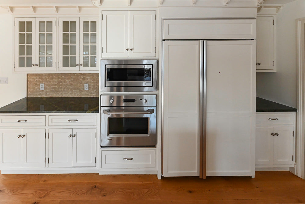 Modern kitchen with white cabinets, stainless steel appliances, and black countertops.