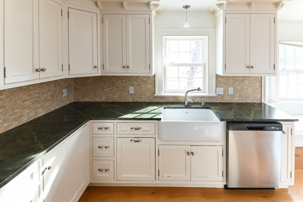 Modern kitchen with white cabinets, black countertops, and stainless steel appliances.