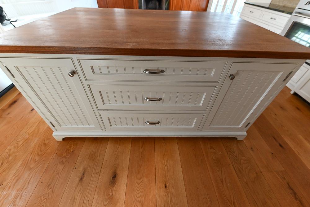 White kitchen island with wooden top in a home setting