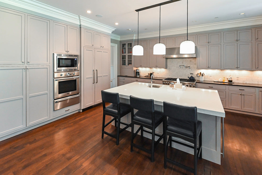 Luxury gray painted custom kitchen island and cabinetry holding integrated Thermador range