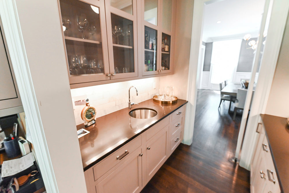 Luxury gray painted custom beverage bar showing upper glass cabinets and under mount sink