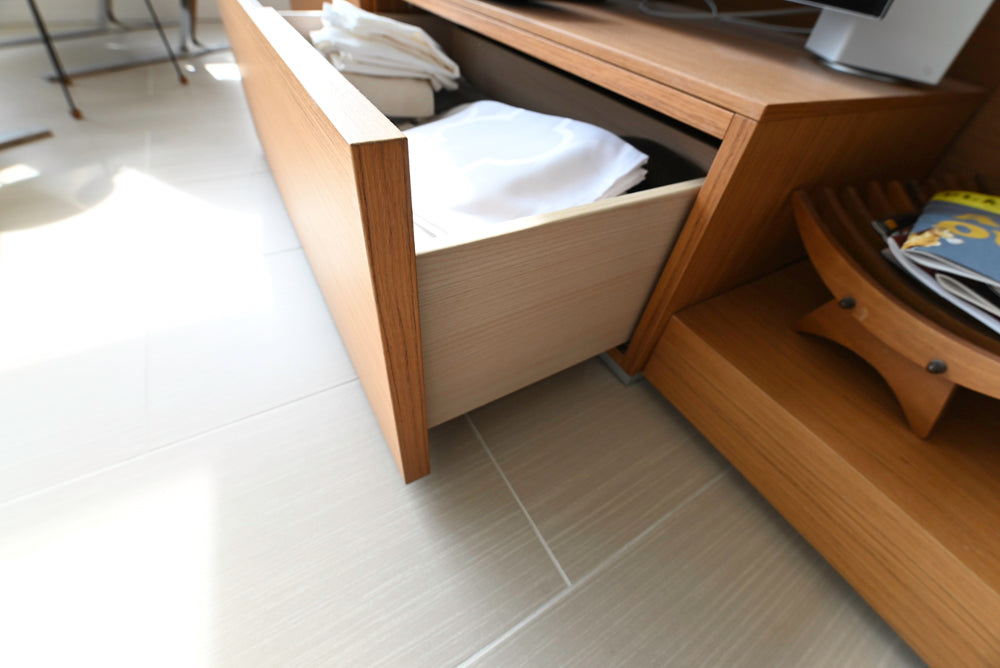 Wooden drawer unit with open drawer on a tiled floor