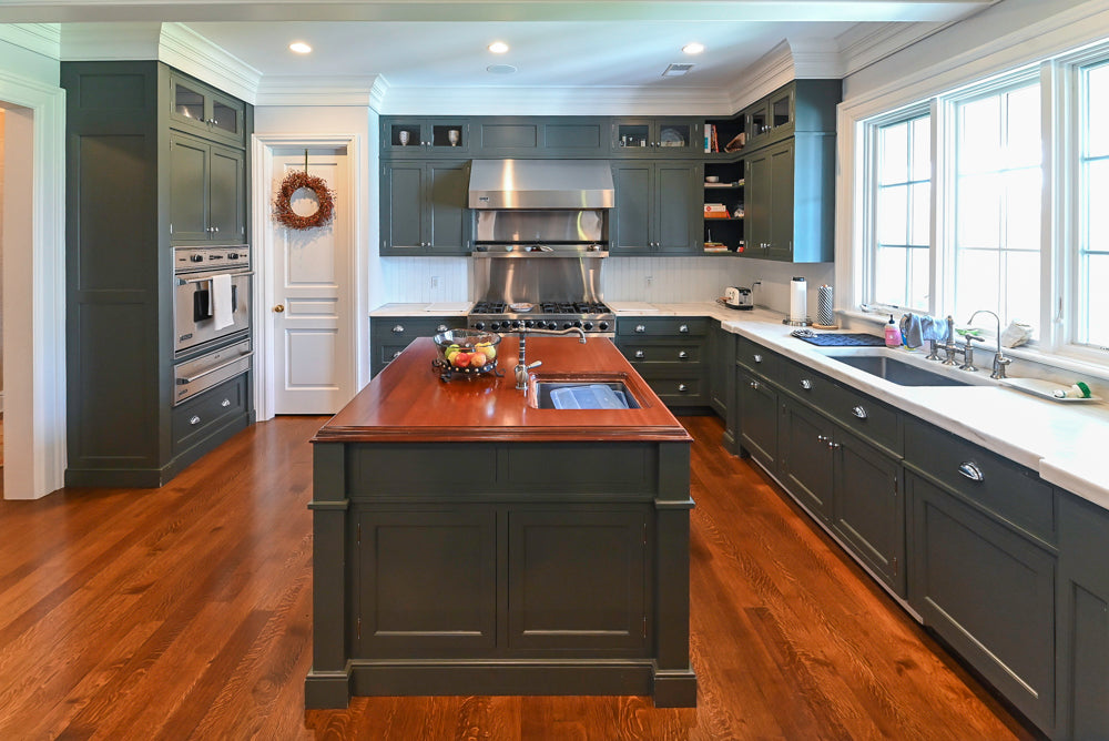 Luxury kitchen island with sage green cabinets and stone countertops