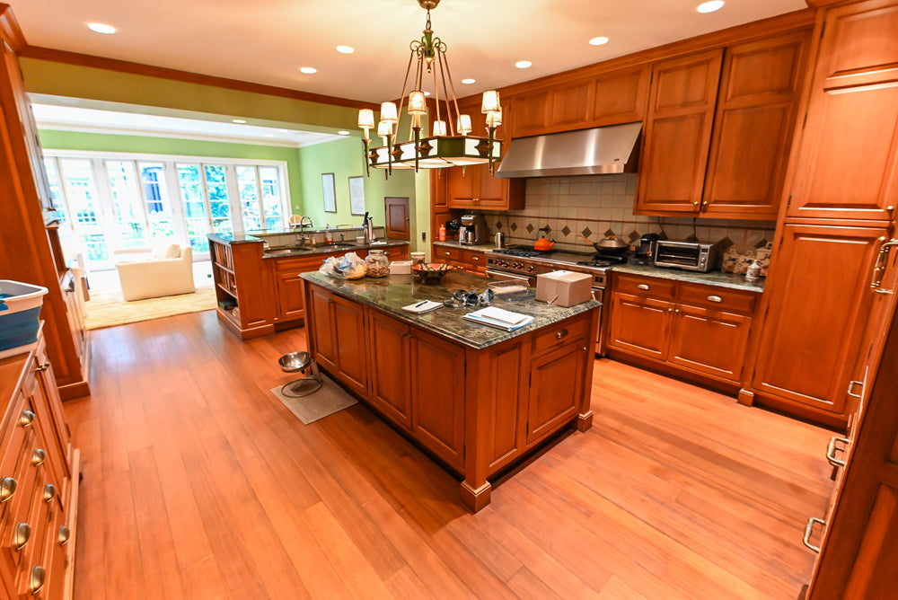 Luxury warm cherry wood kitchen layout showing premium stone countertops and 60 inch Wolf range opening