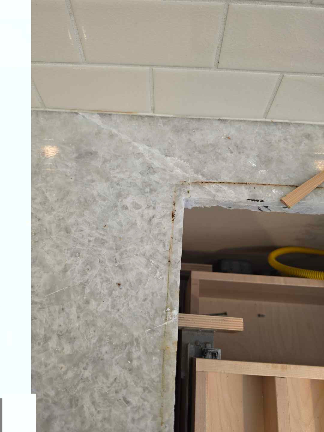 Aurora Circ kitchen installation detail with cream subway tile gray stone surface and exposed wood cabinet framing