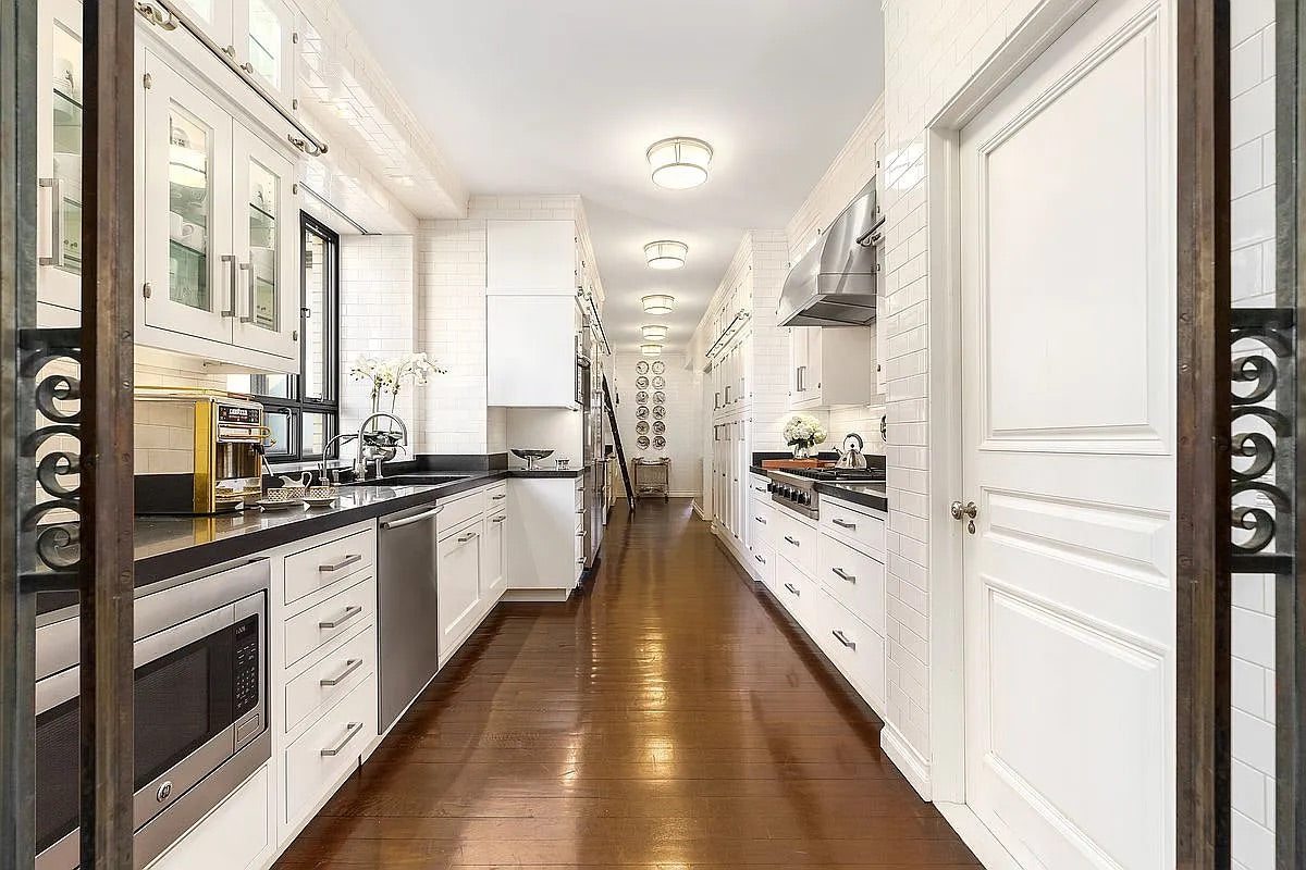 Modern kitchen with white cabinets, black countertops, and stainless steel appliances.