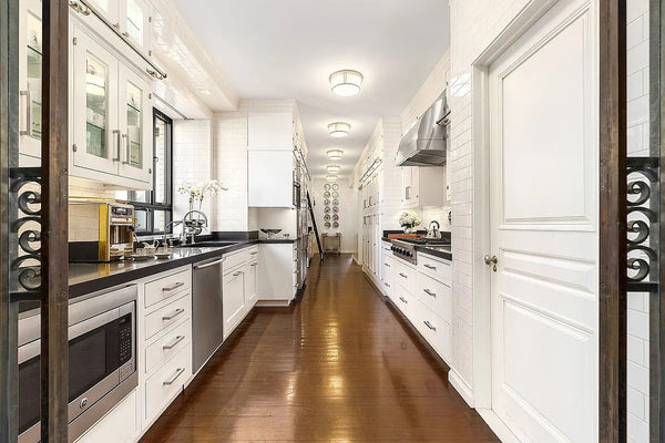 Modern kitchen with white cabinets, black countertops, and stainless steel appliances.