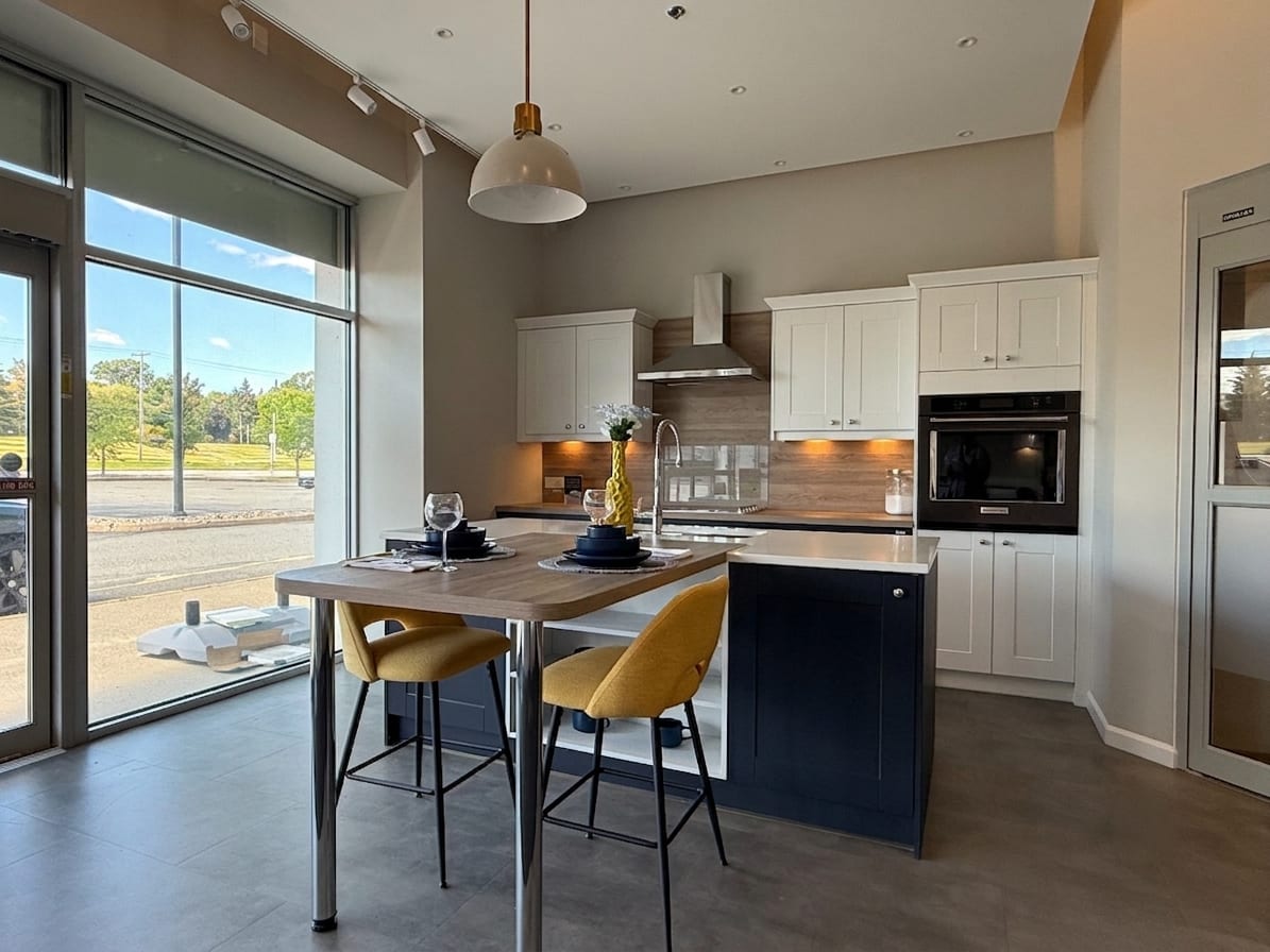 White and navy Wren kitchen display with an island and integrated appliances